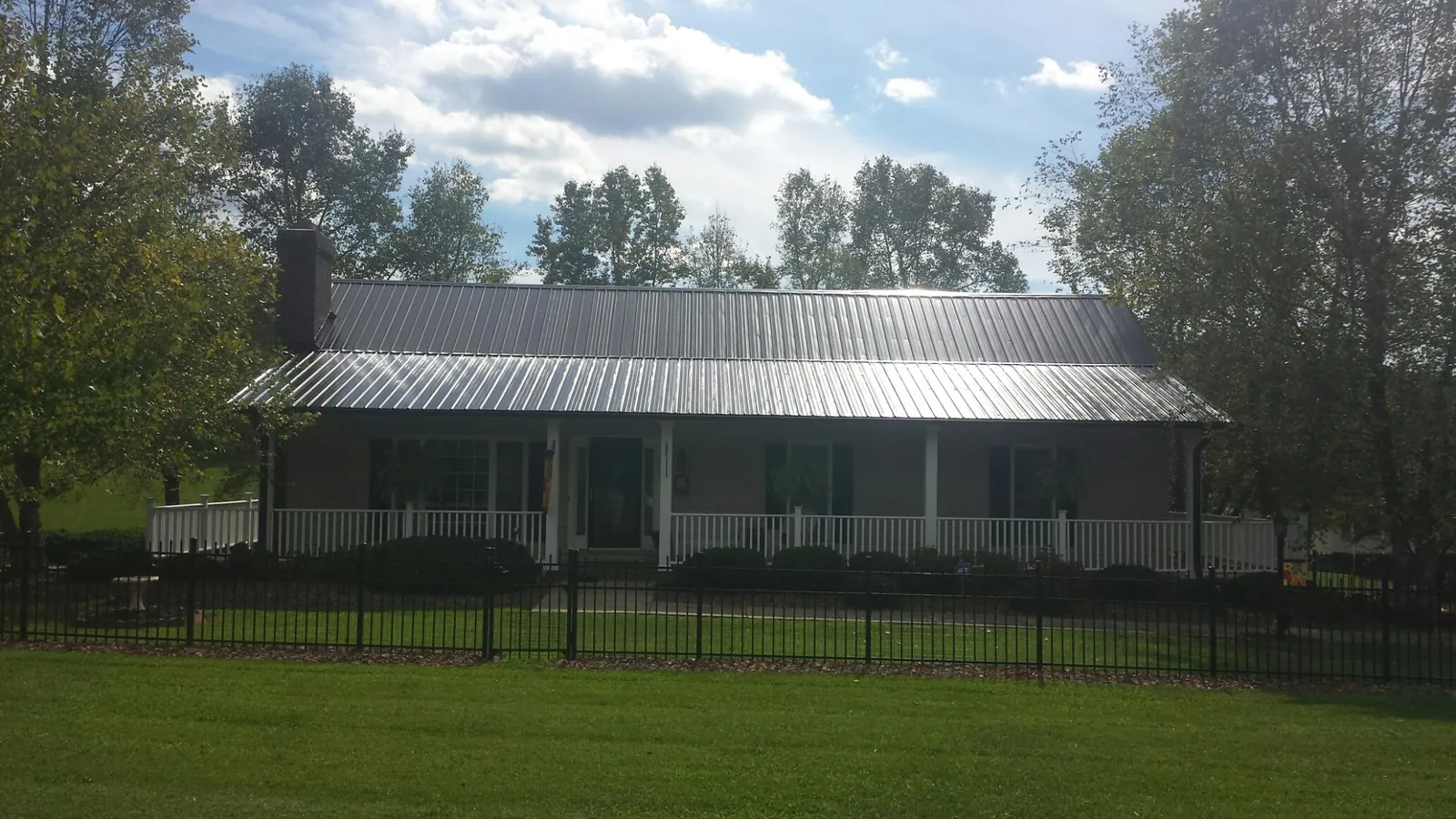 Gray metal roof on a brick ranch with a full width front porch — Gutter Guard Installation work by our crew in Downey